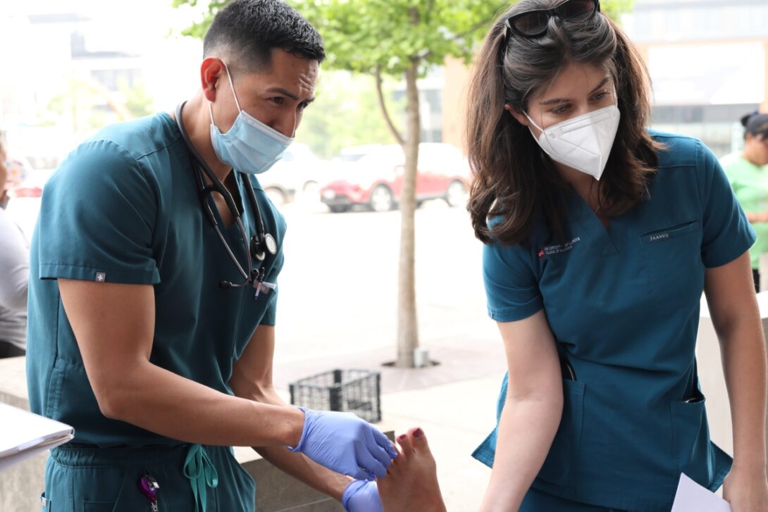 Dr. Alex Lucas and Leena Jehad Abbas treat a migrant outside District 12 police station. (Photo: Jenny Fontaine/University of Illinois Chicago)