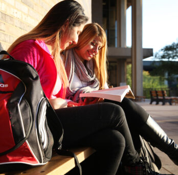 Two latina students reading at SCE 